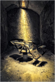An old, rusty electric chair in a dimly lit prison cell.