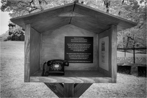 An antiquarian wooden structure shelters a vintage telephone, shrouded in eerie shadows.