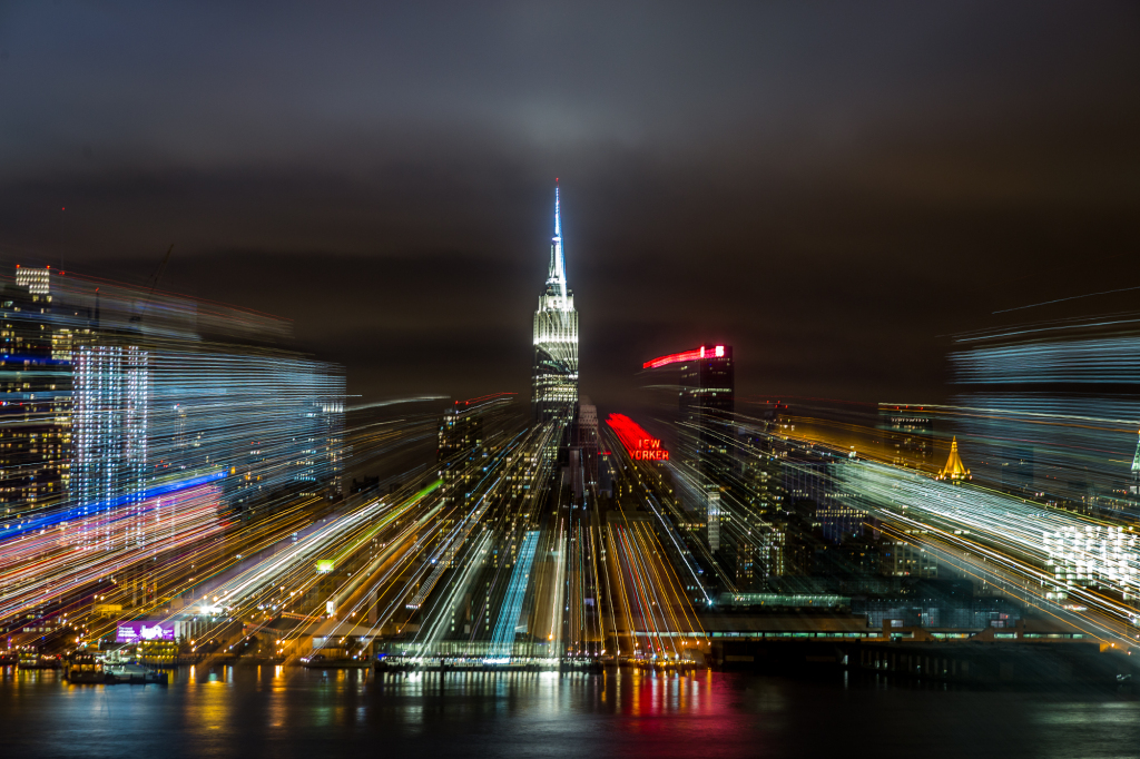 A blurred view of the Empire State Building amidst city lights at night.