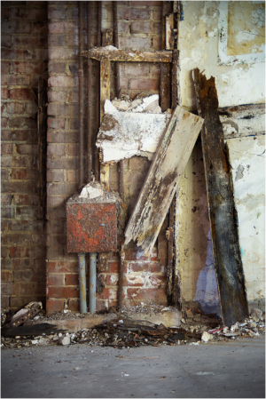 A weathered wall with peeling paint, exposed bricks, and scattered debris.