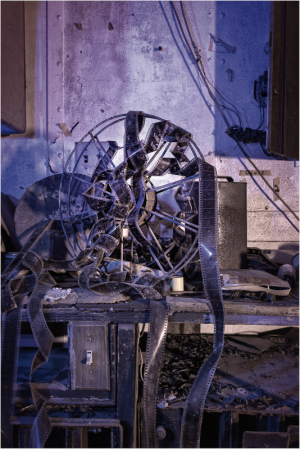 A shattered film reel rests on a dusty table in a decaying theatre.