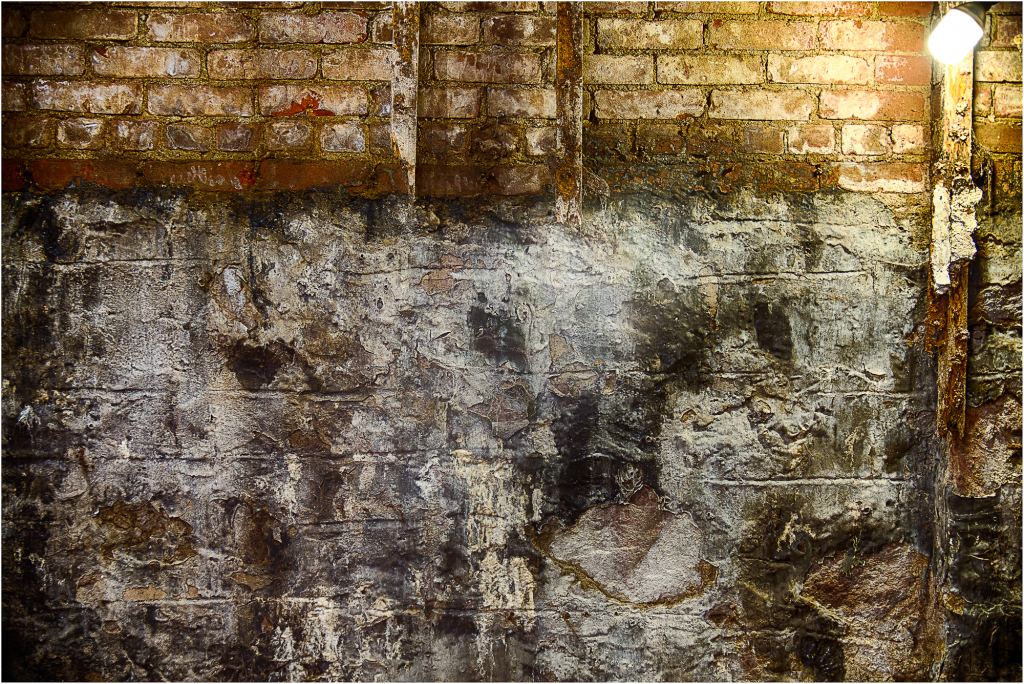 A weathered brick wall, shadows deep and secrets hidden.