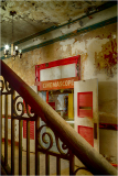 An old theater entrance with red doors and peeling walls, casting shadows in soft light.