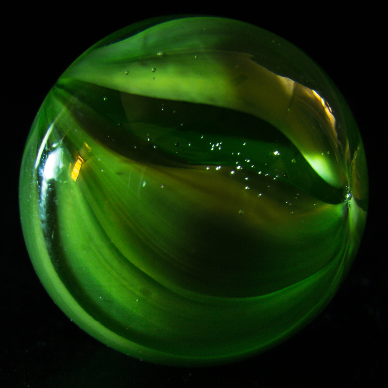 A shiny green marble with swirling patterns and sparkles.
