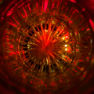 Close-up of a glass with intricate patterns illuminated in red light.