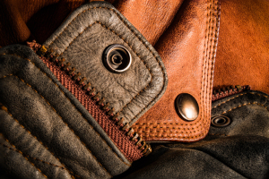 Close-up of textured leather and metal buttons, showcasing rich colors and rugged details.