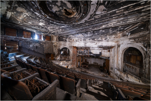 Abandoned theater with peeling paint and empty seats, shadows lurking in corners.