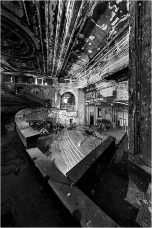 Abandoned theater interior with peeling paint and shadows.