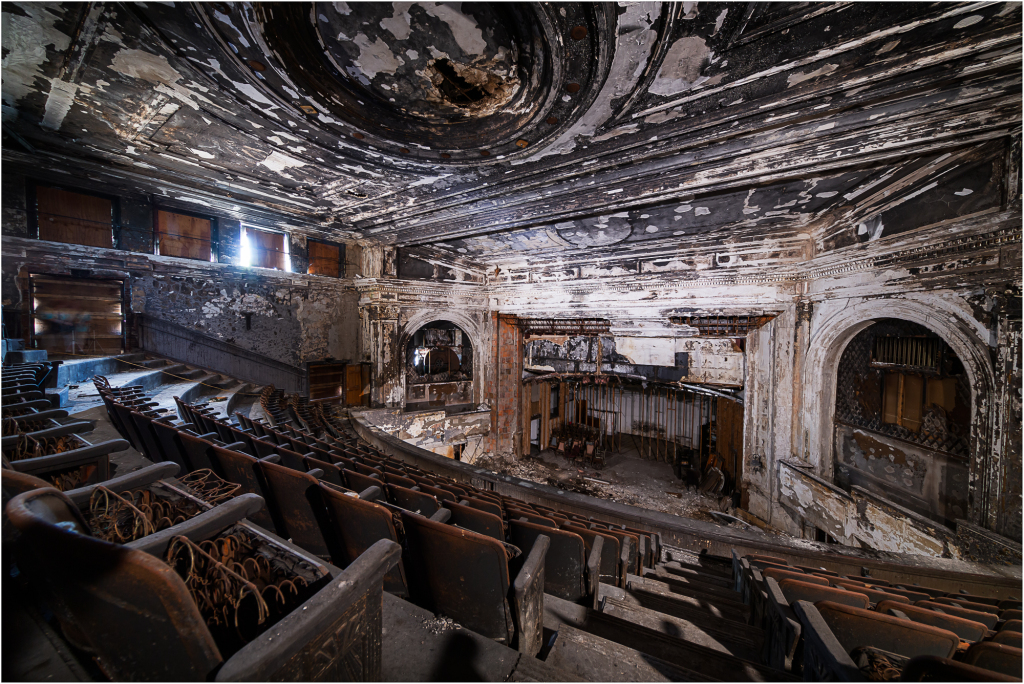 Abandoned theater with peeling paint and empty seats, shadows lurking in corners.