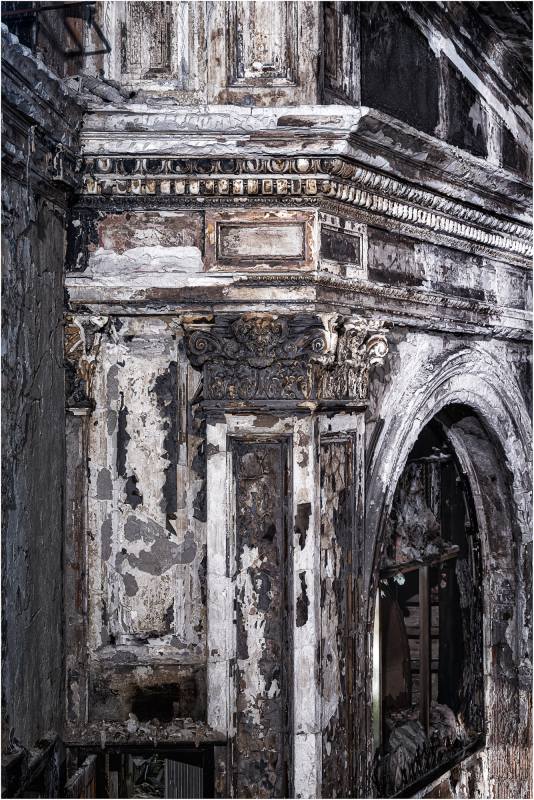 A decaying theater interior with peeling paint and shadows.