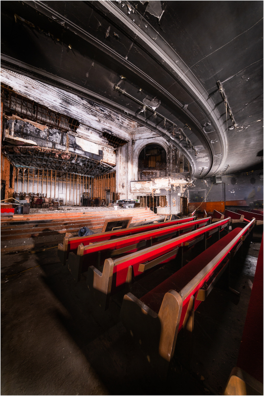 Abandoned theater with empty red seats and peeling walls, shadows lurking in corners.