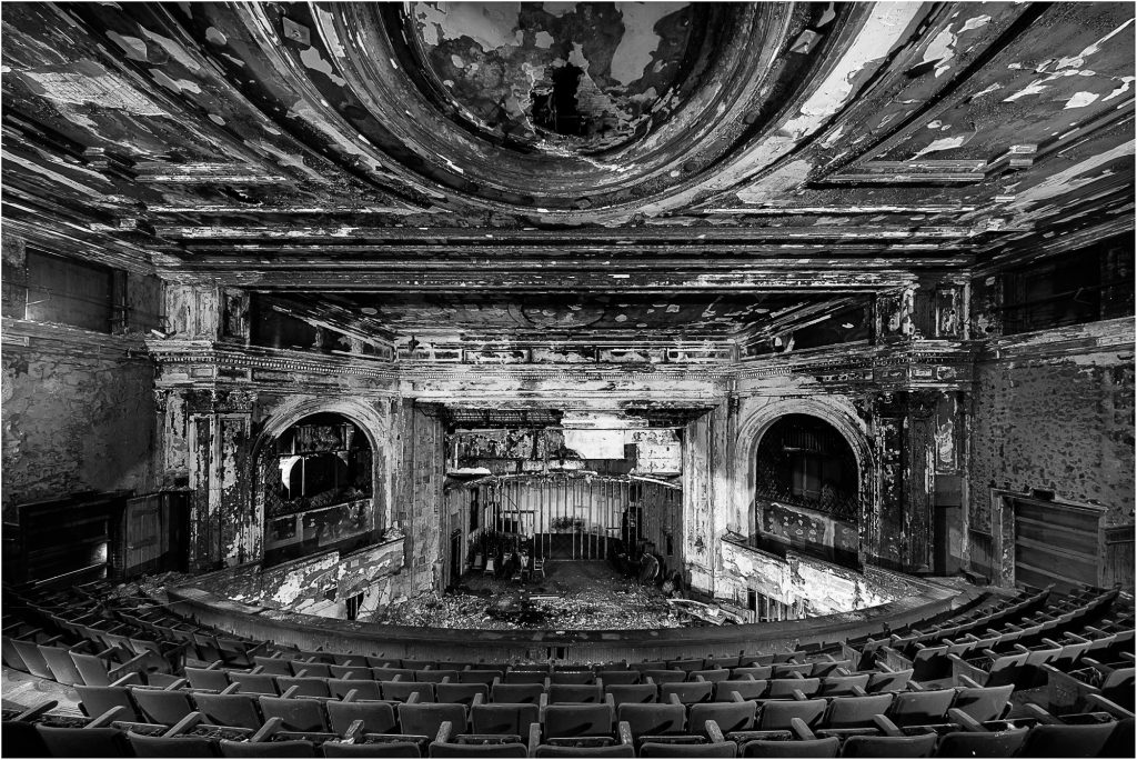 Abandoned theater with peeling paint and empty seats, shadows lurking in corners.