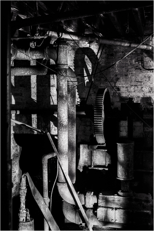 A dark, shadowy corner filled with rusted pipes and machinery.