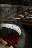 Abandoned theater with peeling walls and empty seats, shadows lurking in the corners.
