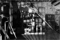 Dimly lit machinery in an abandoned theater, shadows creeping across rusted surfaces.
