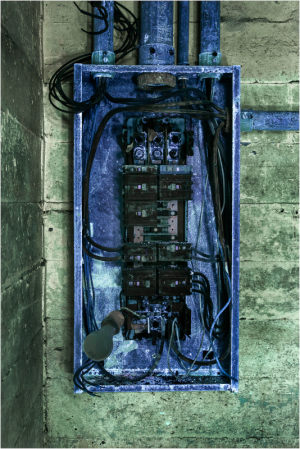 A cluttered electrical panel with tangled wires and switches, showing signs of wear and age.