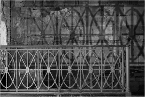 A vintage iron railing casting intricate shadows on a weathered wall.