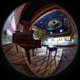 An old piano sits in an abandoned theater, stage lights dimmed, peeling paint on the walls.