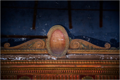 Ornate theater decoration with faded colors and dust, hinting at a glorious past.