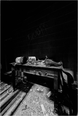 An abandoned workbench covered in dust and debris, with scattered tools and a dark background.