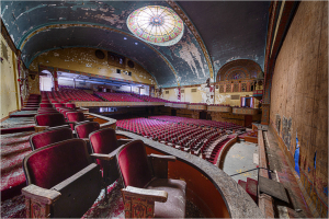Interior of a vintage theater with ornate details and plush red seating.