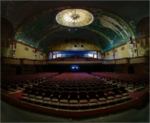 An empty theater with rows of red seats and a colorful ceiling dome.