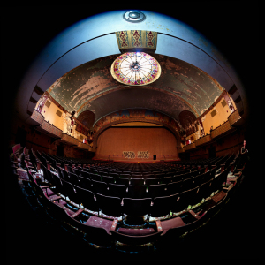 Abandoned theater with peeling paint and empty seats, a haunting beauty remains.