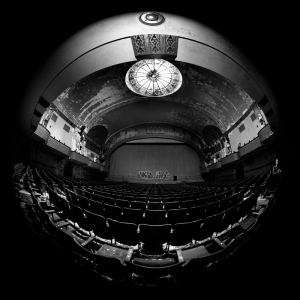 A grand, empty theater with a domed ceiling and ornate details, evoking a haunting atmosphere.