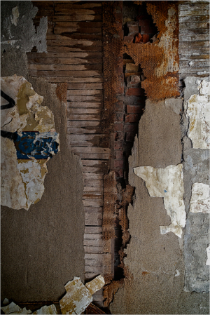Detailed texture of weathered wall with peeling paint and exposed wood.