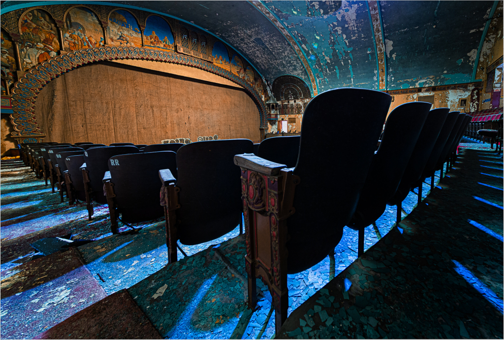 Interior of Irem Temple Theater with empty black seats and a stage curtain in the background.