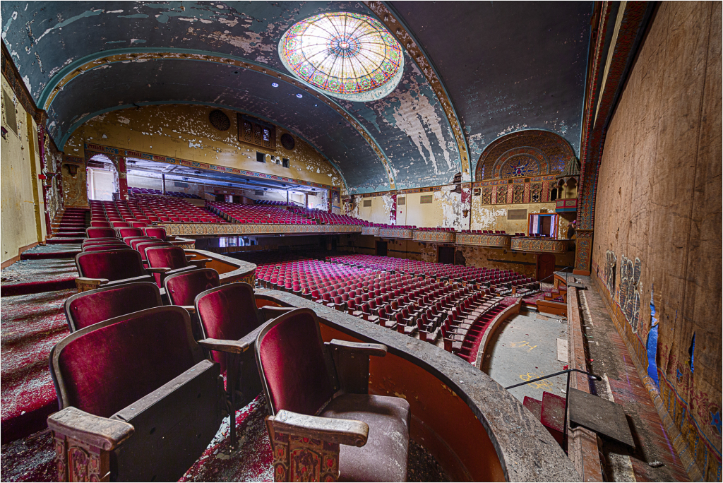 Interior of a vintage theater with ornate details and plush red seating.