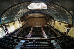 An abandoned theater with ornate ceiling and empty seats, evoking lost grandeur.