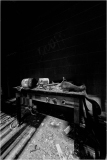 An abandoned workbench covered in dust and debris, with scattered tools and a dark background.