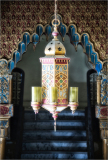 A beautifully ornate lantern hangs in a richly decorated archway.