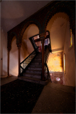 Intricate arches frame a winding staircase leading to a softly lit upper level.