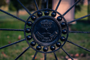 Intricate black ironwork circles, a vintage emblem at the center, surrounded by sharp spikes.