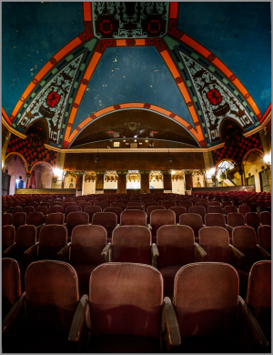 Elegant theater interior with plush seats and a stunning painted ceiling.