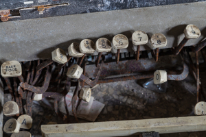 Close-up of rusty metal hooks and numbered tags on a wooden surface.