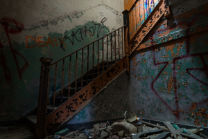 Staircase in an abandoned building with graffiti and debris.