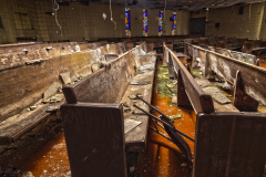 Interior of an abandoned church with damaged pews and stained glass windows