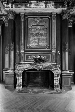 A vintage fireplace with ornate columns and a decorative wall plaque.
