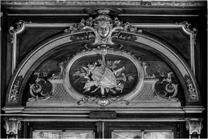 Decorative archway with intricate carvings and a central shield design.