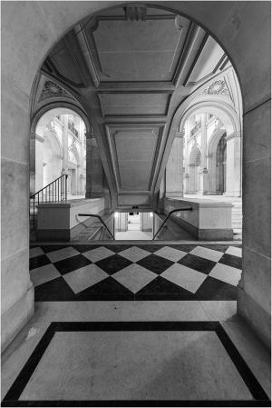 Interior view of a staircase through an arched doorway with patterned floor tiles.