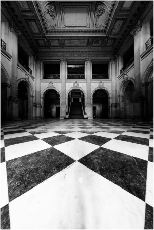 Interior of a grand hall with a checkered marble floor and arched doorways