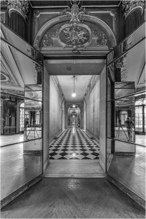 A grand hallway with mirrored walls and a checkered floor, dimly lit and dramatic.