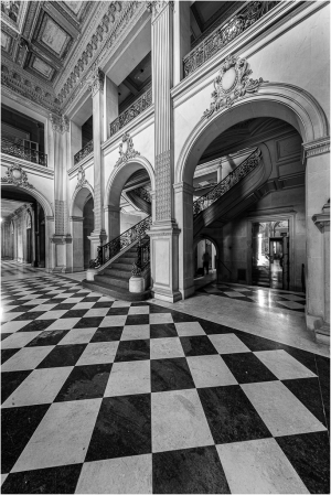 Interior view of a grand hall with arches and a checkered floor