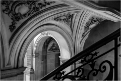 Black and white image of ornate architectural details in a staircase area.