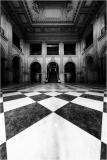 Interior of a grand hall with a checkered marble floor and arched doorways