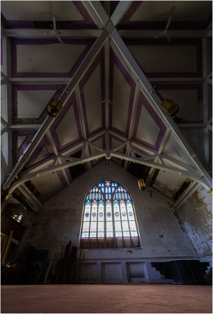 Interior view showcasing a vaulted ceiling with intricate wooden beams and a large stained glass window.