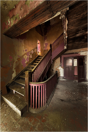 A winding staircase leads to shadowed realms, adorned with peeling paint and whispers of the past.